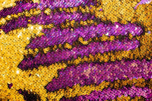 Pulların parlak dokusu renk değiştiriyor. Mor ve sarı. Süslü elbiseler için kumaş.