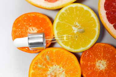 Beyaz arka planda farklı narenciye meyveli C vitamini içeren yüz serumu..