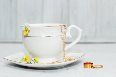 Altın kenarlı, çiçeklerle ve altın mücevherlerle süslenmiş güzel beyaz bir kupa. İş hesabı tasarımı.