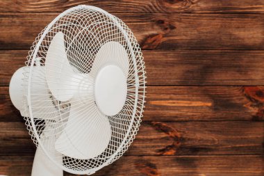 Beyaz pervaneli, ahşap arka plandaki sıcakta odayı soğutmak için bıçaklar..