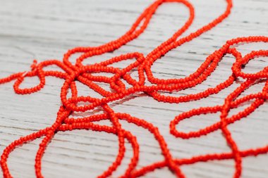 Tahta beyaz arka planda kırmızı boncuklar. Yaratıcılık için boncuklar ve el sanatları.