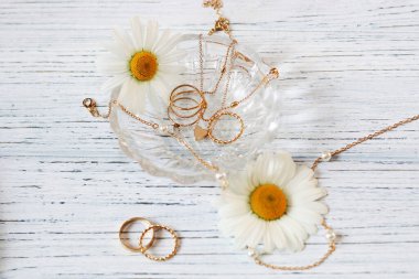 Narin papatyalar altın takılarla yakın plan çekimde. Zincirler, kolyeler, yüzükler stantta.