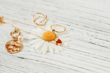 Narin papatyalar altın takılarla yakın plan çekimde. Zincirler, kolyeler, yüzükler stantta.