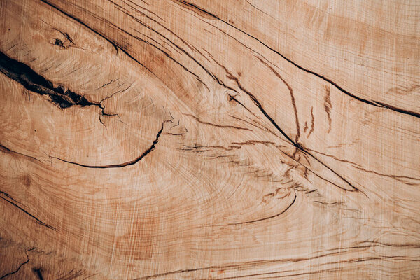 Surface of a wooden board displays rich textures and patterns created by natural grains and knots. The warm hues and fine details highlight the beauty of natural wood.