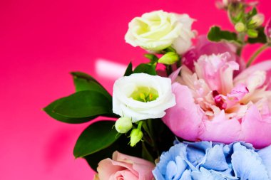 Güzel bir buket, güller ve ortancalar gibi yumuşak pastel çiçeklere sahiptir. Yeşil yapraklar tazelik katar. Düzenleme canlı pembe bir arka plana karşı duruyor ve canlı bir atmosfer yaratıyor..