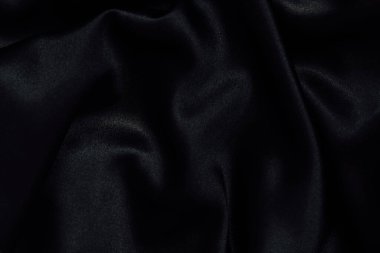 Yumuşak kıvrımlar halinde uzanan zengin siyah bir kumaş pürüzsüz ve ipeksi bir doku sergiliyor. Işık lifleri yakalar yumuşak gölgeler yaratır ve zarif örtüsünü vurgular..