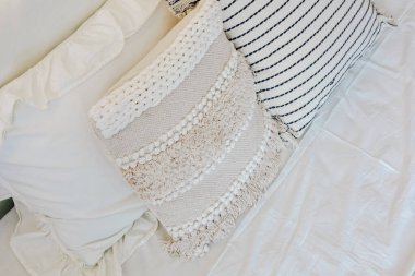 Sıcak ve davetkar bir yatak odası yumuşak yumuşacık yastıklarla birlikte açık renkli bir yatak örtüsü üzerine dokulu bir yastık içerir. Bu kombinasyon dinlenmek için mükemmel rahatlatıcı bir atmosfer yaratır..