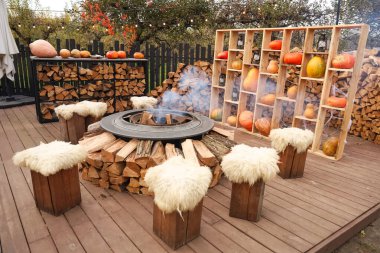 Davetkar bir açık hava alanında, ahşap banklarla çevrili, yumuşak koltuklu dairesel bir ateş çukuru bulunuyor. Sonbahar toplantıları için ateş çukuru ve balkabağı ekran alanı