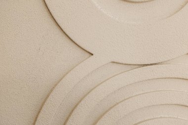 The scene presents a close up of a wall with a unique texture showcasing circular patterns in soft cream and beige tones. The design creates a visually appealing abstract effect.