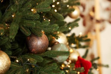The close up view of a Christmas tree shows rich green branches filled with sparkling lights and golden ornaments. A cozy atmosphere is created perfect for holiday celebrations and gatherings.