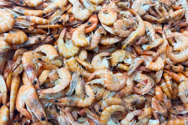 Hareketli bir deniz ürünleri pazarı satışa hazır büyük bir taze karides yığınına sahiptir. Satıcılar ve müşteriler balık pazarlarının canlı atmosferini vurgulayan renkli ekranın etrafını sardılar.