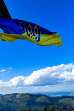 Canlı bir Ukrayna bayrağı bir dağın zirvesinde rüzgarda dalgalanıyor..