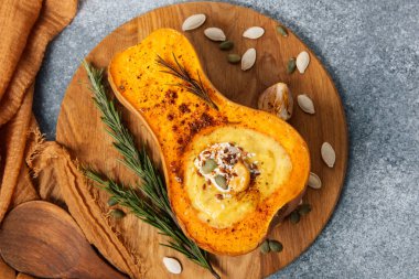 Kızarmış tereyağlı ezmenin yarısı kremalı ve fındık ve tohumlarla kaplı ahşap bir tepside duruyor. Taze otlar ve baharatlar sağlıklı bir yemek için hazır olan zengin lezzetini arttırır..