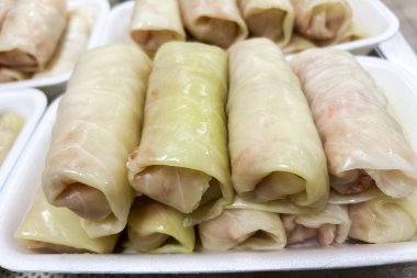 Lahana ruloları, lezzetli et ve pirinçle dolu çeşitli rulo ekmeklerin sergilendiği tepsilerde güzelce düzenlenir..