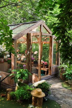 Bahçede çeşitli bitki ve çiçeklerle bir sera duruyor. İçerideki insanlar camdan gelen güneş ışığının ve çevrenin tadını çıkarıyorlar. Bölge ağaçlar ve taşlarla dolu..