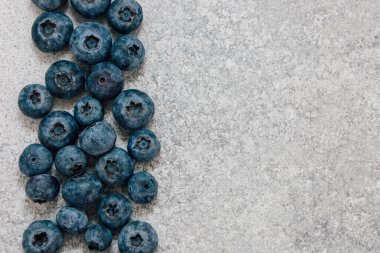 Yabanmersini gri bir taş yüzeyde yakın bir şekilde toplanır. Yuvarlak meyveler zengin renklerini ve eşsiz şekillerini sergiler. Ayarlar yaratıcı kullanım için basit bir arkaplan sunar.