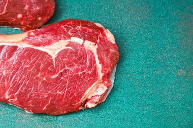 Taze bir parça sığır eti, mutfaktaki yeşil bir kesme tahtasının üzerinde duruyor. Et mermer renginde ve pişirilmeye hazır. Ayarlar yemek hazırlamaya odaklanmamızı söylüyor..