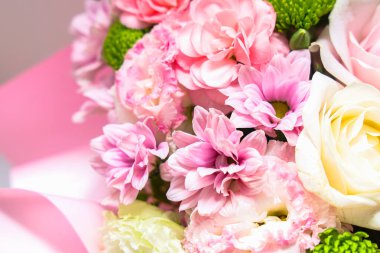 Pembe çiçek ve yeşillik koleksiyonu parlak bir alana yerleştirilmiş bir buketi doldurur. Çiçekler çeşitli şekil ve boyutlarda sergileniyor. Kutlamalar için uygun görsel olarak çekici bir düzenleme oluşturuyorlar..