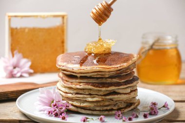 Tahta masadaki siyah arka plandaki krep yığınına akan bal. Yan Görünüm.