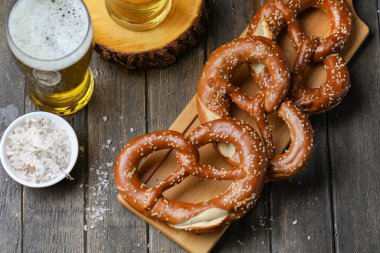 Geleneksel tuzlu krakerler ve susam tohumları ve tahta zeminde altın bira..