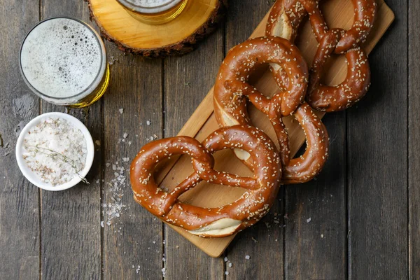 Geleneksel tuzlu krakerler ve susam tohumları ve tahta zeminde altın bira..