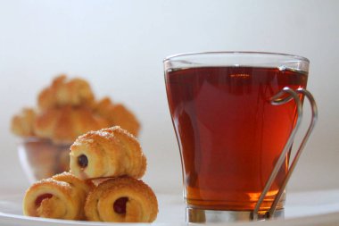 Beyaz tabakta marmelatlı kruvasanla bir bardak çay. Yan Görünüm, Yakın Yaklaş.