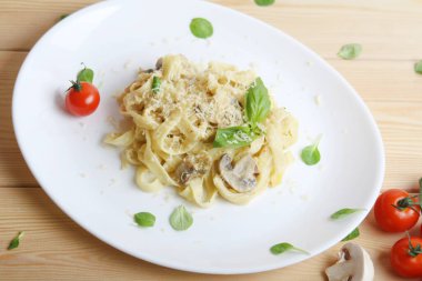 İtalyan Fettuccine peynirli, mantarlı, domatesli, fesleğenli ahşap tabakta. Üst Görünüm.