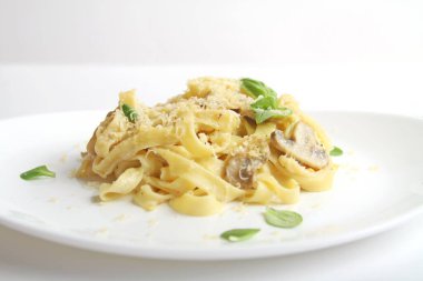 İtalyan Fettuccine peynirli, mantarlı, fesleğenli, beyaz tabakta. Yan Görünüm.