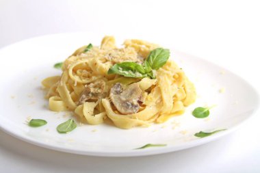 İtalyan Fettuccine peynirli, mantarlı, fesleğenli, beyaz tabakta. Yan Görünüm.