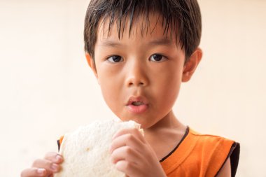 Oğlan sandviç ekmek yiyor.