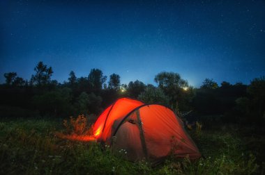 yıldızlı gökyüzü altında içinde kırmızı çadır aydınlatma
