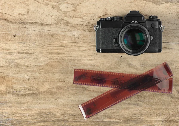 Camera en fotografische 35 mm Filmstrip op houten achtergrond — Stockfoto