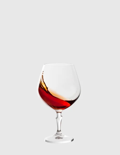 Glass with brandy and splashes isolated on light grey background — Stock Photo, Image