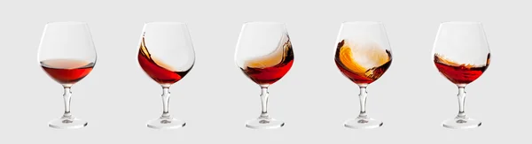 Set of brandy glasses with splashes isolated on light grey backg — Stock Photo, Image