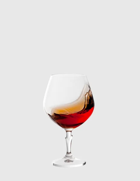 Glass with brandy and splashes isolated on light grey background — Stock Photo, Image