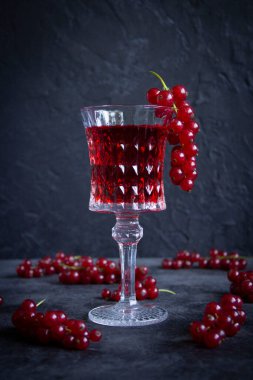 Kırmızı üzümlü bir bardak (alco / n / a) ve çimento yüzeyi üzerinde bir avuç üzümlü üzümlü.