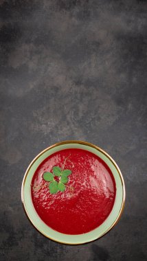 Üzerinde pancar kremalı çorba ve mikroyeşil bezelye olan bir kasenin üst görüntüsü.