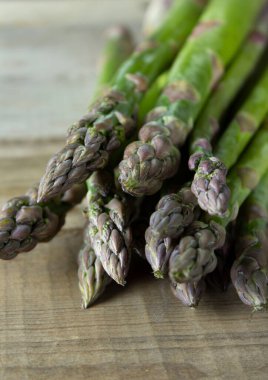 Kırsal ahşap bir masada bir sürü yeşil çiğ kuşkonmaz.