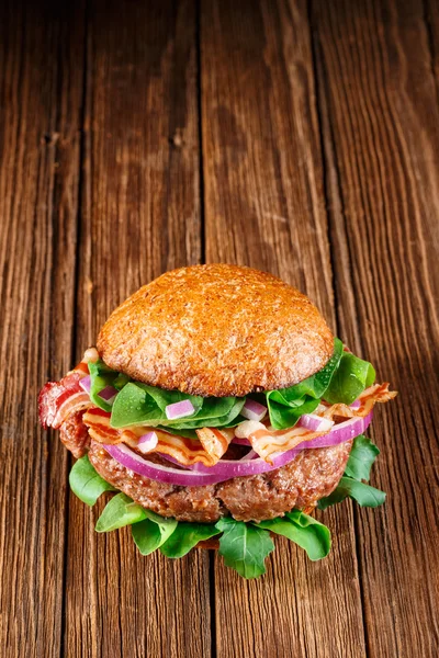 Burger with bacon on wooden background. — Stock Photo, Image