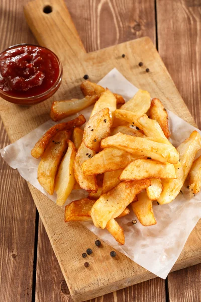 Batatas fritas na placa de corte de madeira velha Imagem De Stock