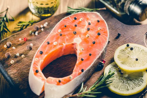 Filete de salmón crudo en tabla de cortar de madera —  Fotos de Stock