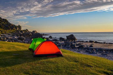 Norveç 'in Lofoten Adaları' ndaki Uttakleiv plajında gün batımında çadır kurmak.