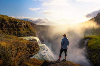 İzlanda 'daki Gullfoss şelalesinin kenarında duran genç yürüyüşçü.