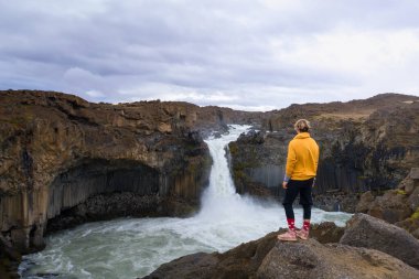 Yürüyüşçü İzlanda 'daki Aldeyjarfoss şelalesine bakıyor.