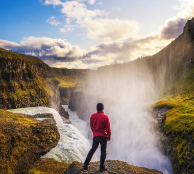 İzlanda 'daki Gullfoss şelalesinin kenarında duran genç yürüyüşçü.