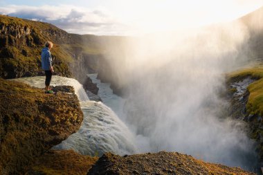 İzlanda 'daki Gullfoss şelalesinin kenarında duran genç yürüyüşçü.
