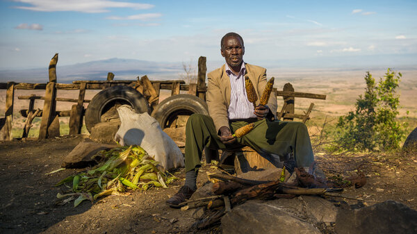 African man in a suit sells corn  near the Great Rift Valley in 