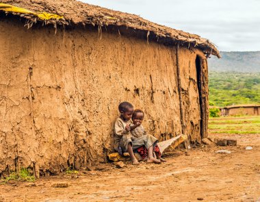  İki erkek bir Masai kabilesi köy evinin önünde oturan