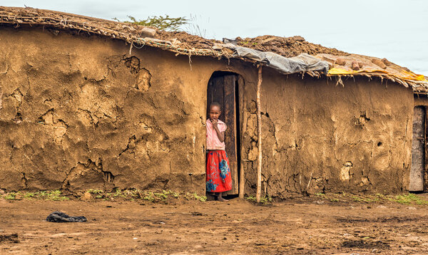 MAASAI MARA, KENYA - OCTOBER 17, 2014 : Young african girl from masai tribe in the doorway of her home. The Maasai are a Nilotic ethnic group living in southern Kenya and northern Tanzania