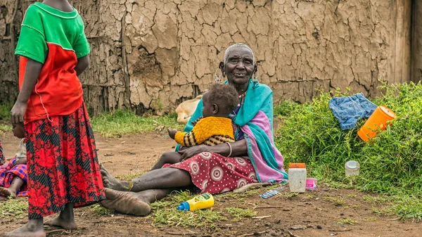 Vieja mujer africana sosteniendo a un bebé en su pueblo — Foto de Stock
